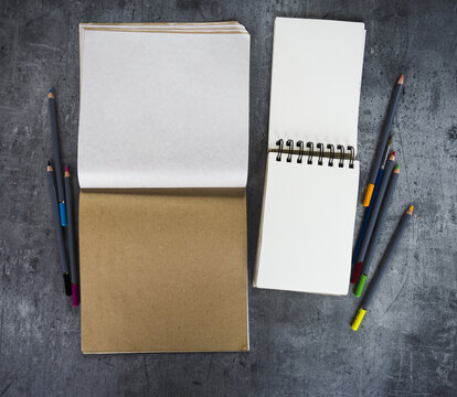 Top view of open kraft paper notebook  and  open spiral A6 sketchbooks on a grey stone background.