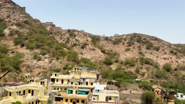 View of Amer Fort village and the historic wall stretching across the hills in Jaipur, Rajasthan, India.