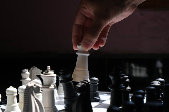Chess game. Lifting the queen and ready to move to overthrow the opponent's queen (selective focus). World Chess Day