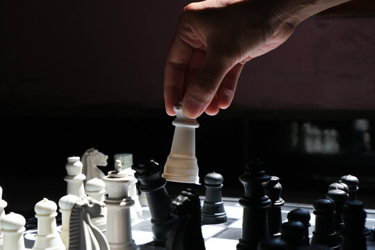 Chess game. Lifting the queen and ready to move to overthrow the opponent's queen (selective focus). World Chess Day