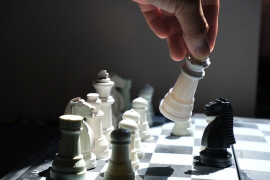 Chess game. Lifting the queen and ready to move to overthrow the opponent's queen (selective focus). World Chess Day