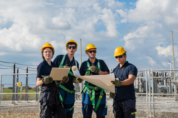 Fototapeta premium Successful electrical engineer teamwork holding blueprint and laptop looking forward at industrial power plant site. Commercial energy infrastructure business and construction safety management.