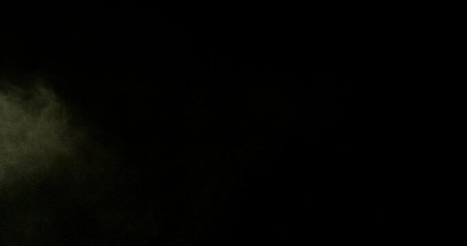 Ultra slow motion dust or sand cloud drifting through the air on a black background. Particle explosion effect ideal for overlays, compositing, visual effects, motion graphics and VFX projects.