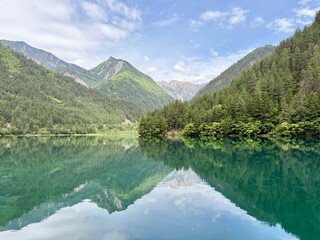 Fototapeta premium Stunning reflection of lush green mountains on the turquoise lake in Jiuzhaigou National Park, China - in June, summer