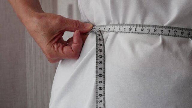 Senior woman Measuring waist with tape measure, weight loss and healthy lifestyle concept.