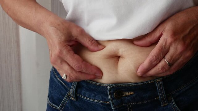 Senior woman pinching belly fat, weight loss and obesity concept.