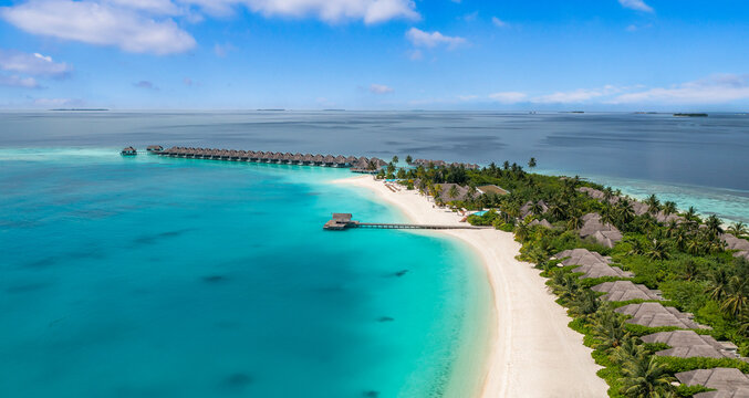 Stunning aerial Maldives island scenery. Overwater villas and turquoise lagoon from above. Tropical paradise seascape reef and white sand. Luxury travel destination banner, summer vacation drone view