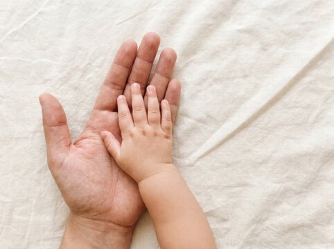 adult hand holding baby on linen fabric family love care connection