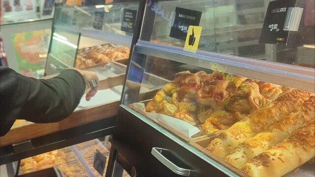 Assorted freshly baked bread and pastries inside a glass display counter at a local bakery shop"
