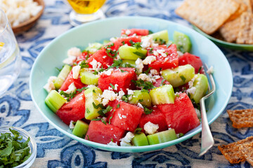 Naklejka na ściany i meble Fresh summer watermelon salad with feta cheese and cucumber in blue bowl. Azulejo baclground. Close up.