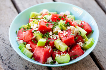 Obraz premium Refreshing summer appetizer featuring juicy watermelon cubes and salty feta cheese for outdoor picnic concept. Wooden background. Close up.