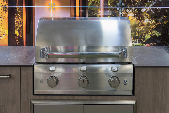 Built-in stainless steel gas grill with closed hood and control knobs