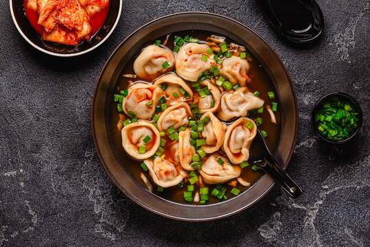 Dumplings served in a bowl with broth and green onions.