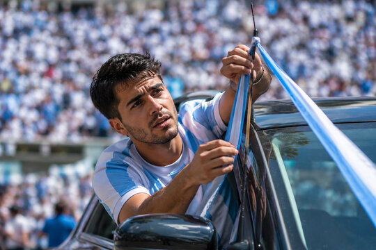 Young argentinian fan fixing flag to car window on sunny day during celebration