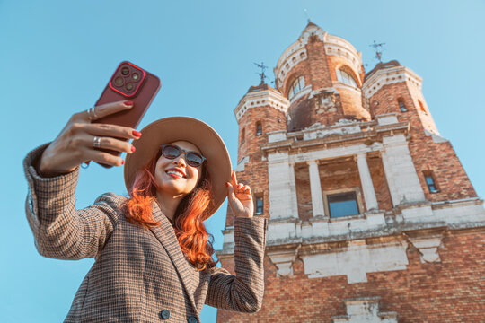 Young woman smiling while taking a selfie with her smartphone, visiting Gardos Tower, a historic landmark in Zemun, Belgrade