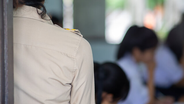 Teacher Invigilating Examination with Students Blur in Classroom Background