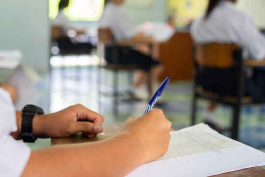 High School Student Taking Standardized Test with Concentration on Wooden Desk
