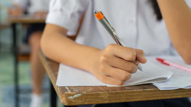 High School Student Taking Standardized Test with Concentration on Wooden Desk