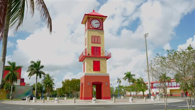 Red and beige clock tower at Lauderhill sports complex under cloudy sky