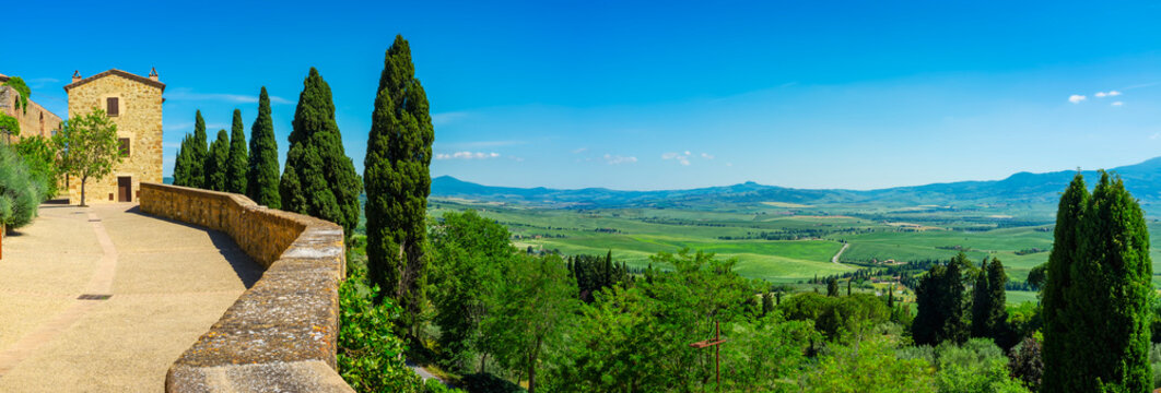 Wide panoramic view of the hills and countryside surrounding the village of Pienza (Tuscany village, Italy) seen from its medieval fortified walls, during early summertime.