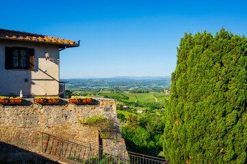 Naklejka premium Panoramic view of the hills and countryside surrounding the village of San Gimignano (Tuscany village, Italy), covered by olive trees and vineyards, during early summertime.