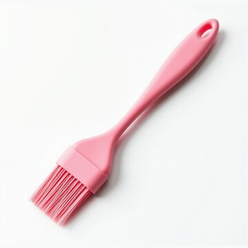 Pink silicone pastry brush lies on white background. This kitchen tool is great for baking basting and basting meat or pastries. Useful for cooking.