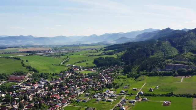 4K aerial view of Turie village in Zilina region, Slovakia. Beautiful panoramic shot of countryside houses, green fields, and the D1 highway bridge with Mala Fatra mountains background