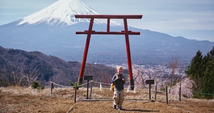 Happy kid with backpack looking at view from torii gate hill and walking away - slow motion shot