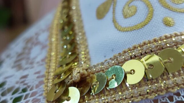Close-up of white lace fabric with golden embroidery and sequins