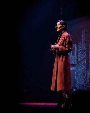 Powerful actress delivering an intense monologue on a dark theatrical stage. Cinematic lighting highlights a solo performance with a film noir mystery concept and copy space.