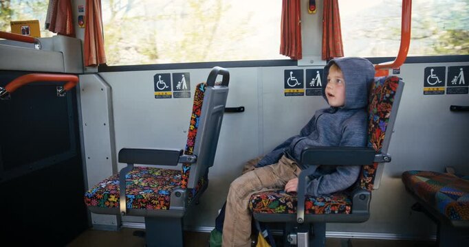 Happy, lone boy in hoodie riding Japanese train - medium, side shot