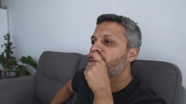 Depressed man covering himself with blanket lying down on couch to sleep and escape reality