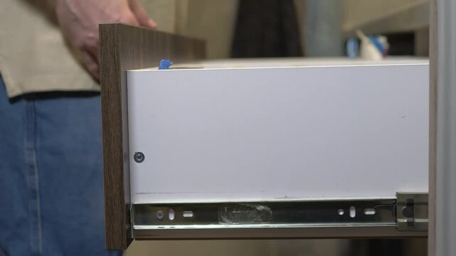 Opening a furniture drawer in a house. A man opens a storage drawer.