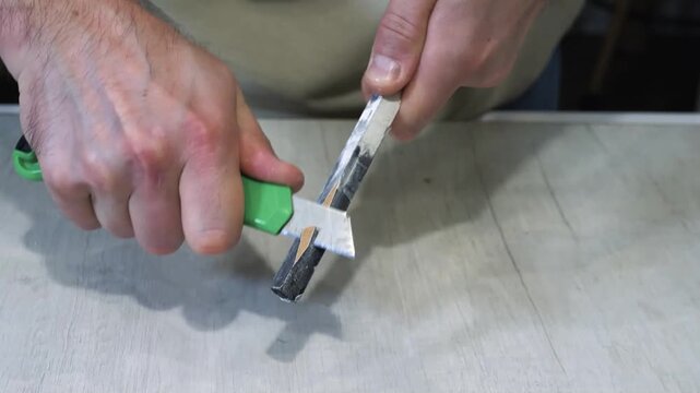 Sharpening a board for a year, a man sharpens a thin piece of wood with a stationery knife.