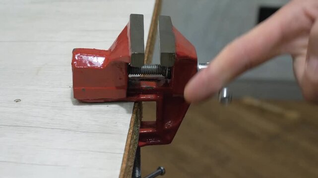 A mini vice on a workbench, a worker opens the metal vice