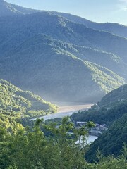 A serene landscape featuring lush green mountains surrounding a winding river. The scene captures the tranquility of nature in a remote area. © Катерина Крюгер