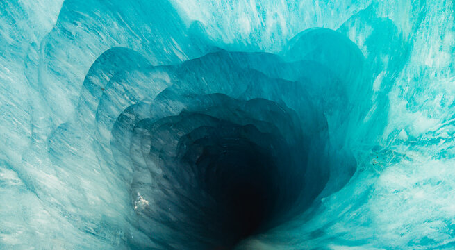 Deep blue glacier moulin inside Mer de Glace ice cave, French Alps