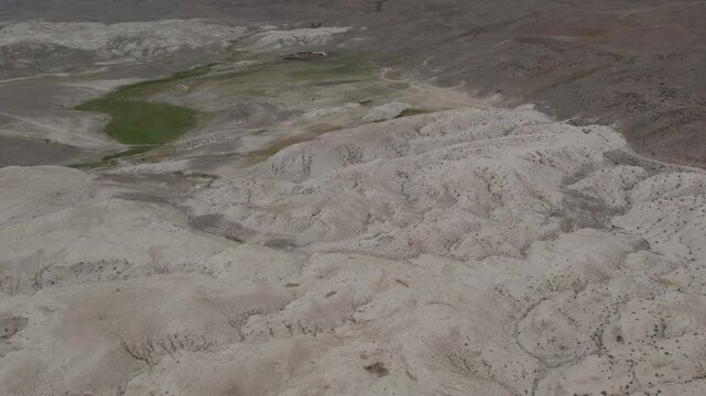 Drone footage of the Moon Landscape badlands with pale clay hills and sparse vegetation near Kosh-Agach, Altai Republic, Russia, remote arid steppe terrain