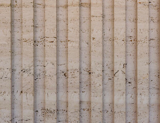 Unfilled travertine stone texture with vertical fluted grooves and natural limestone character suitable for elegant interior walls and architectural surface design © IULIIA