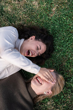 Two young women laughing together on grass outdoors