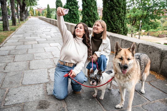 Two women taking a selfie while walking dogs in a park
