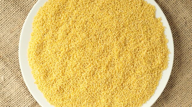 White plate with raw millet rotating