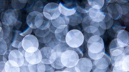 Abstract luxury background with soft blue and silver bokeh circles glowing on a dark texture. © Igor