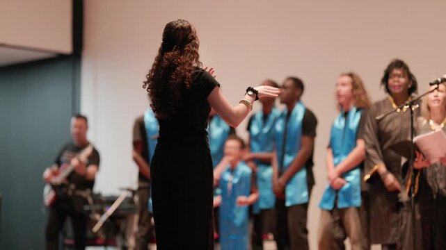 Woman choir conductor leading gospel singers on stage