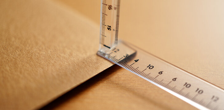 Measuring with a clear plastic ruler on a flat brown paper surface measurement centimeter precision stationery geometry engineering architectural education distance drafting planning