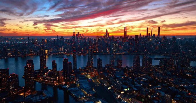 Bright burning sky over the scenery of New York City. Flight over New Jersey with the view on Manhattan across the river.