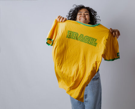 Brazilian Latina woman celebrating with a Brazil jersey for the World Cup in a photo studio. Rio de Janeiro, Brazil.