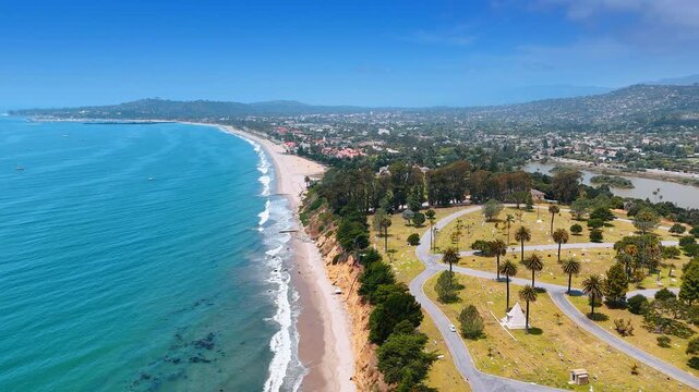 Rising over the sandy beach of the Pacific Ocean on sunny day. Revealing view on the beautiful park at the shore of Santa Barbara, California, USA.