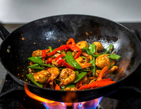 Salteado de camarones y vegetales en wok con fuego en cocina profesional