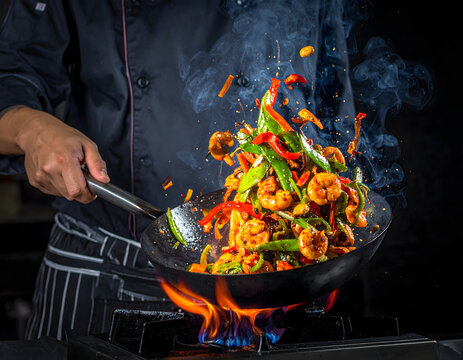 Salteado de camarones y vegetales en wok con fuego en cocina profesional